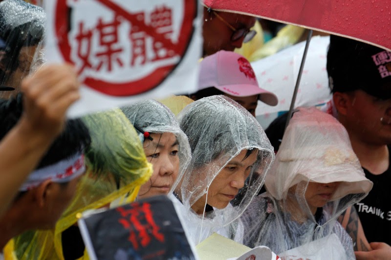 Protesters gather in the rain during a rally against pro-China media in front of the presidential office building in Taipei on June 23, 2019.